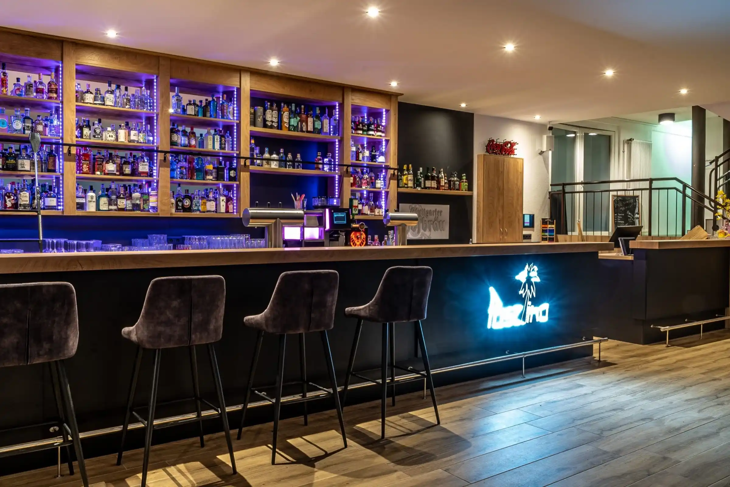 Bar mit Hockern und leuchtendem Paselino-Logo